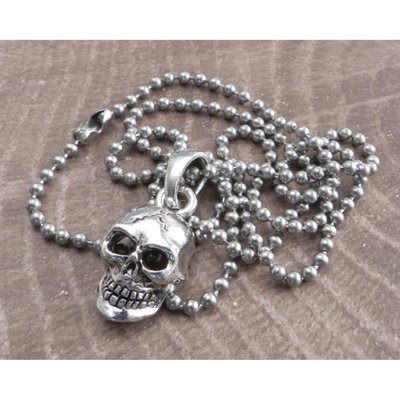 "The Amigaz Skull Pendant strung on a Stainless Steel ball chain necklace. The skull pendant is a detailed all sided pendant. It is a solid, substantial with a large matching movable bail for the perfect lie. This stunner of a pendant is finished off with our sterling silver antique plating. Featuring Stainless Steel ball chain is approx. 30" , 3mm thick with a B-coupling snap on-off clasp.*Skull Pendant measures approx.  . 1 1/4""L by 3/4""W"